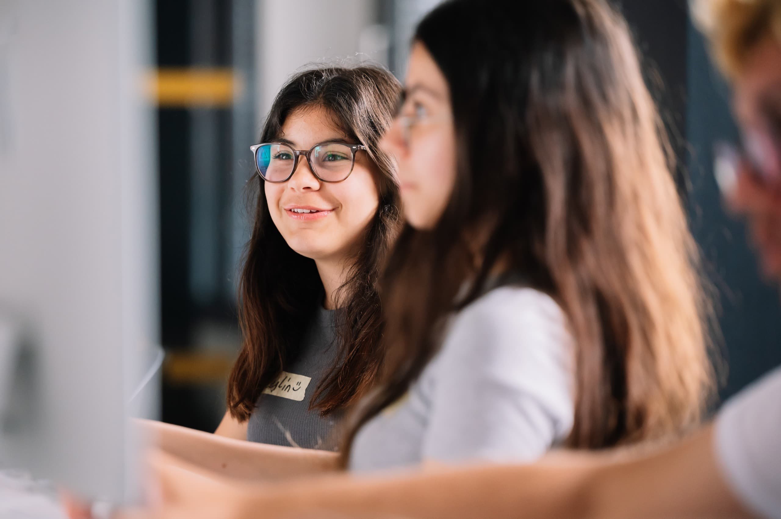 Schüler*innen und Erwachsene arbeiten gemeinsam an einem Tisch im TUMO-Zentrum.
