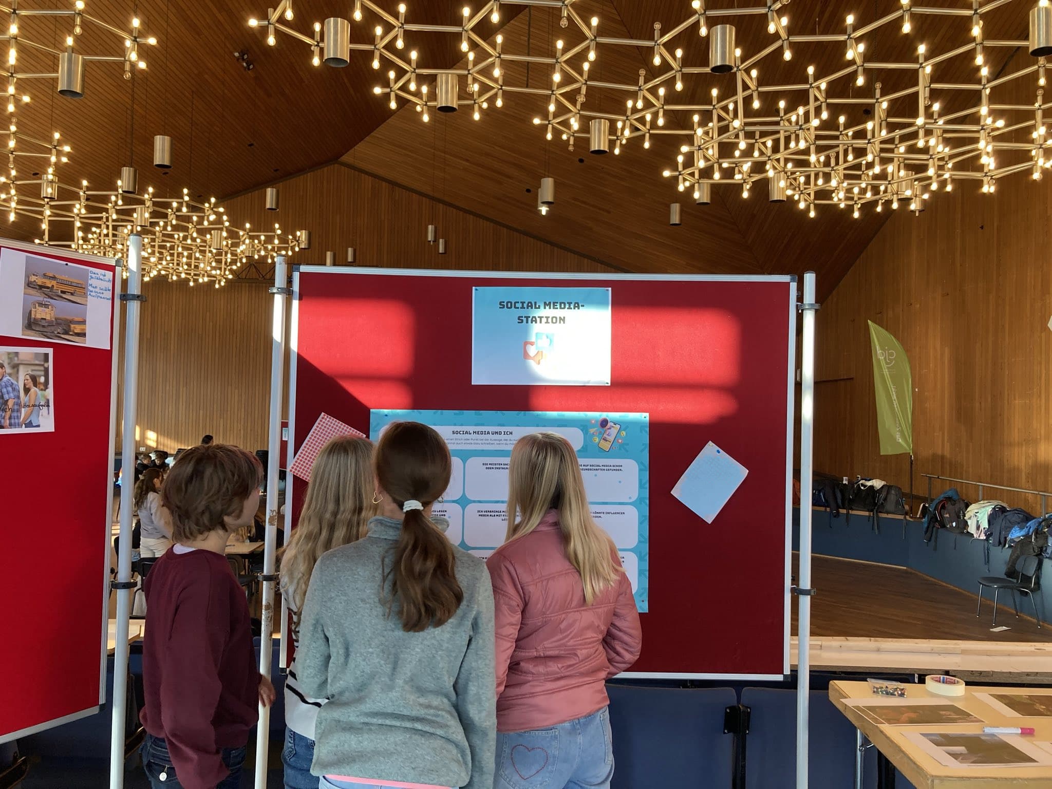 Kinder und Jugendliche nehmen an einer Social-Media-Station in einer Veranstaltungshalle teil.