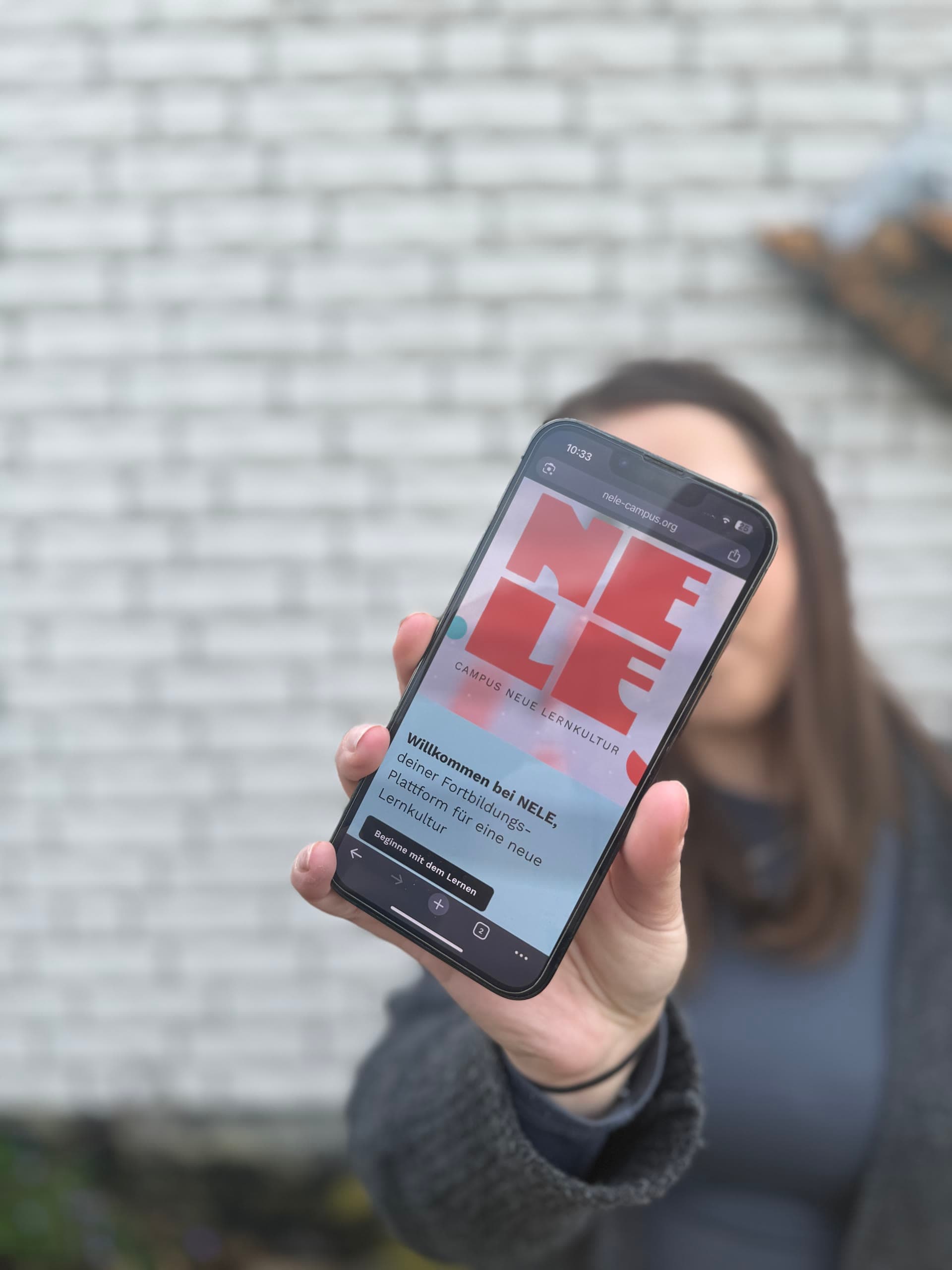 Die Website des NELE-Campus wird auf einem Smartphone gezeigt.