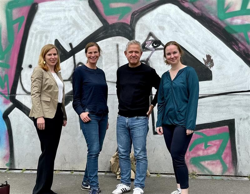 Vier Personen stehen vor einer bemalten Wand in Berlin.