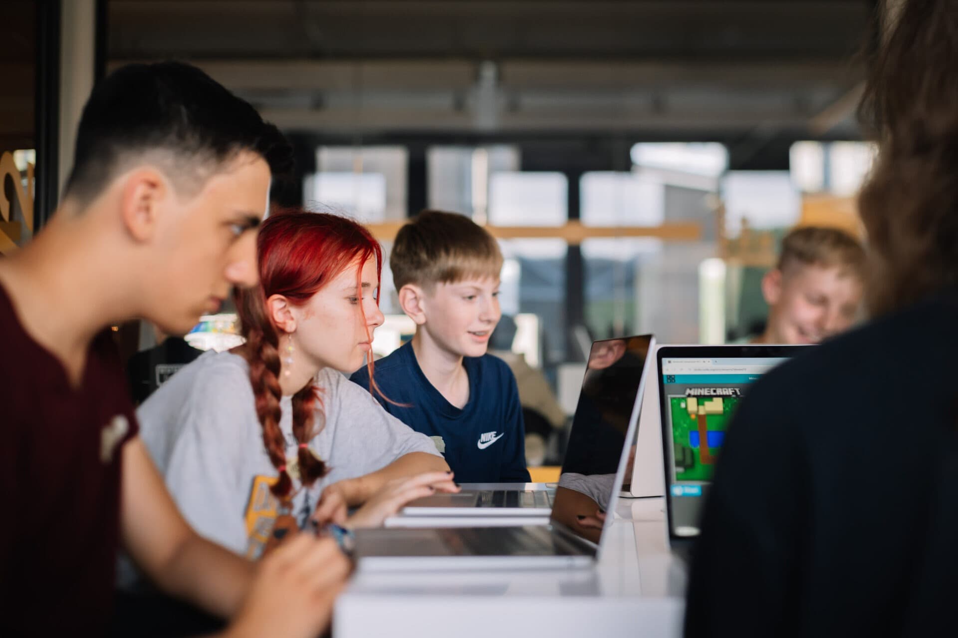 Schüler*innen arbeiten gemeinsam an Laptops.